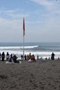 The Indonesian flag fluttering in the midst of the activities of people relaxing and enjoying the scenery by the beach