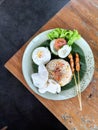 Indonesian Fried Rice with Satay, Egg, and Crackers on a Rustic Wooden Table Royalty Free Stock Photo