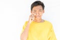 Indonesian guy with a yellow t-shirt wiping the tears off his face on a white background Royalty Free Stock Photo