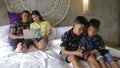 Indonesian or malasian family addicted to digital technology. Family at home using smartphones. Mom, dad and children