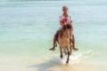 Indonesian man riding a horse on the beach