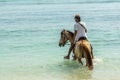 Indonesian man riding a horse in the shallow water close to the