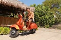 Indonesian man sitting on traditional italian scooter.Orange old-fashioned motorbike, indonesian traditional way of transportation Royalty Free Stock Photo