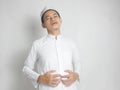 Indonesian Muslim men wear gray skullcap and white robe touch his stomach satiated eating too much break the fast. Full. Stuffed Royalty Free Stock Photo