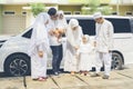 Indonesian muslim multi-generation family standing by a car