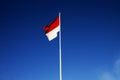 Indonesian national flag (red and white) flying against a blue sky background. Royalty Free Stock Photo