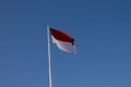 Indonesian national flag (red and white) flying against a blue sky background. Royalty Free Stock Photo