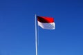 Indonesian national flag (red and white) flying against a blue sky background. Royalty Free Stock Photo