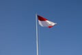 Indonesian national flag (red and white) flying against a blue sky background. Royalty Free Stock Photo