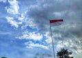 Indonesian national flags against blue sky. Red white flag flies on a pole