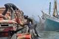 Indonesian port workers unload a ship with a cement bags cargo