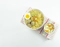 Indonesian Warm noodles served with fresh tomatoes and meatballs on a white round bowl and pickles on a white bowl on a white