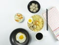 Indonesian Warm noodles served with fresh tomatoes and meatballs on a white round bowl and pickles on a white bowl on a white