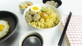 Indonesian Warm noodles served with fresh tomatoes and meatballs on a white round bowl and pickles on a white bowl on a white