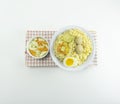 Indonesian Warm noodles served with fresh tomatoes and meatballs on a white round bowl and pickles on a white bowl on a white