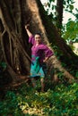 An Indonesian woman bravely poses while raising her hands in a purple dress