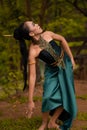 An Indonesian woman poses with black hair dangling to the ground while wearing a green dance costume