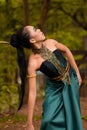 An Indonesian woman poses with black hair dangling to the ground while wearing a green dance costume