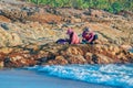 Indonesian women sort the fishing catch by sitting on a rock by the sea in the evening. Sea surf. Concept of aboriginal life.