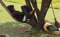 Indonesian worker sleeping on tree branch, Jakarta