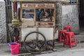 Indonesian young woman sits a a food pushcart in a street of Jakarta