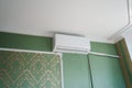 Indoor air conditioning unit on the wall of the apartment with green wallpaper Royalty Free Stock Photo