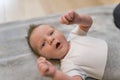 Indoor closeup portrait of a little infant baby boy clenching his fists and yawning with open mouth and eyes. Dark thin Royalty Free Stock Photo