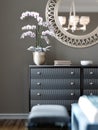 Indoor flowering plant in a pot on a cabinet and a mirror on the wall. Modern bedroom interior