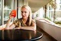 Indoor lifestyle fashion portrait of beautiful woman posing at cafe, drinking fresh healthy non-alcoholic cocktail, smiling, have Royalty Free Stock Photo