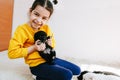 Indoor photo of happy child playing at home with little black dog. Pretty little girl with the puppy. Adorable kid playing with Royalty Free Stock Photo