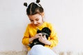 Indoor photo of a happy child smiling and playing at home with little dog. Cute little girl cares about the puppy. Adorable kid Royalty Free Stock Photo