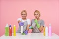 Indoor photo of lovely young white-headed housewives being in nice mood while making spring cleaning, sitting over pink background