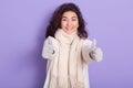 Indoor photo of positive adorable young black haired cute woman making gesture, showing sign super with two hands, looking