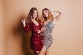 Indoor photo of two joyful girls drink champagne and fooling around during christmas party. Blissful european ladies