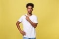 Indoor photo of young African American man pictured isolated on grey background pointing to his white blank T-shirt Royalty Free Stock Photo