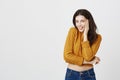 Indoor portrait of attractive cute dark-haired woman in trendy cropped sweater smiling sensually at camera while holding