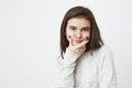 Indoor portrait of attractive european girl with interested look, holding hand on chin, thinking about something