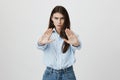 Indoor portrait of attractive stylish woman stretching hand at camera with stop or hold sign, looking concerned and Royalty Free Stock Photo