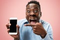 Indoor portrait of attractive young black man holding blank smartphone