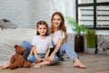 Indoor portrait of a beautiful mother with her charming little daughter posing against bedroom interior. Royalty Free Stock Photo
