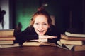 Indoor portrait of beautiful redhead woman learning or reading books in university Royalty Free Stock Photo