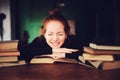 Indoor portrait of beautiful redhead woman learning or reading books in university Royalty Free Stock Photo