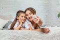 Indoor portrait of a beautiful mother with her charming little daughter posing against bedroom interior. Royalty Free Stock Photo