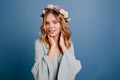 Indoor portrait of carefree young woman with shiny blonde hair. Studio shot of magnificent white girl with flower wreath Royalty Free Stock Photo