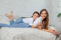 Indoor portrait of a beautiful mother with her charming little daughter posing against bedroom interior. Royalty Free Stock Photo