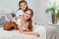 Indoor portrait of a beautiful mother with her charming little daughter posing against bedroom interior. Royalty Free Stock Photo