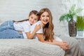 Indoor portrait of a beautiful mother with her charming little daughter posing against bedroom interior. Royalty Free Stock Photo