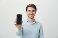 Indoor portrait of funny and handsome young guy bending right with hands on head and charming smile, expressing Royalty Free Stock Photo