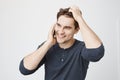 Indoor portrait of handsome young sportsman talking on smartphone while touching his hair and looking aside, standing Royalty Free Stock Photo