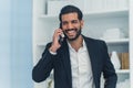 Indoor portrait of a laughing handsome dark-haired bearded Cuban businessman in a suit talking to his client. Royalty Free Stock Photo